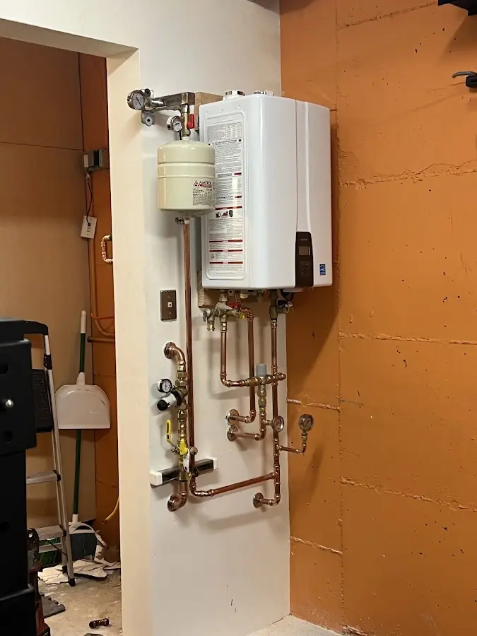 Plumbing technician inspecting water heater connections in New Philadelphia